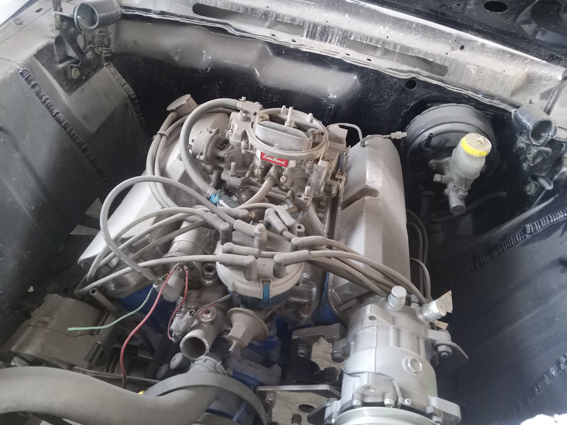 Classic engine bay with carburetor and accessory drive during a garage build supported by PSS.