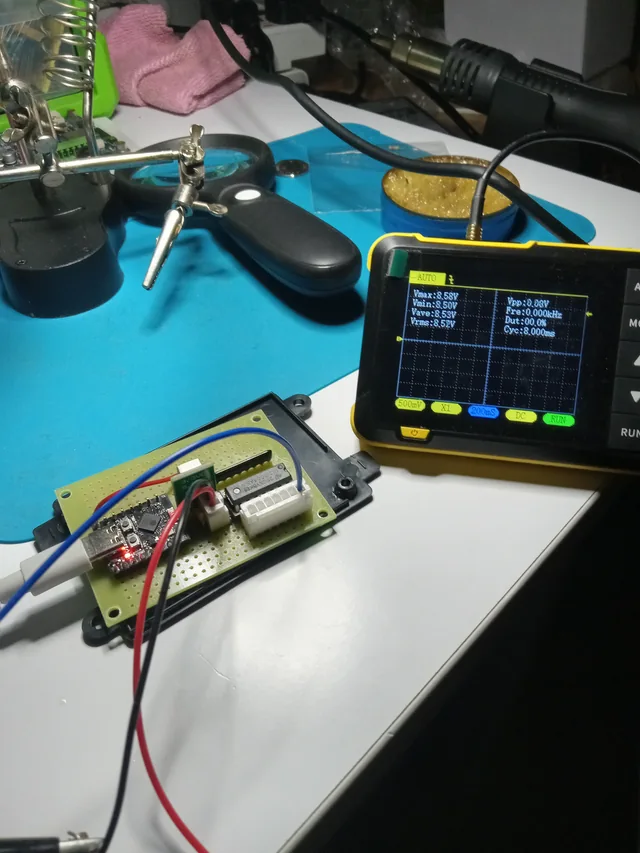 A powered controller prototype beside an oscilloscope during bench measurement.